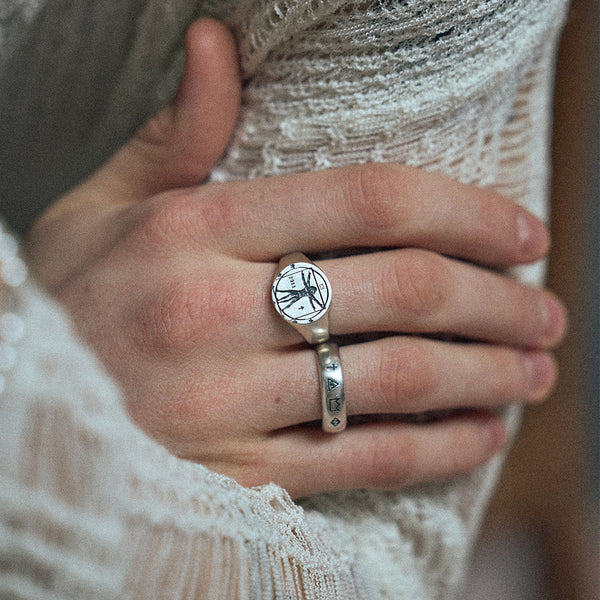 Models hand holding light knitwear with 2 rings on his fingers