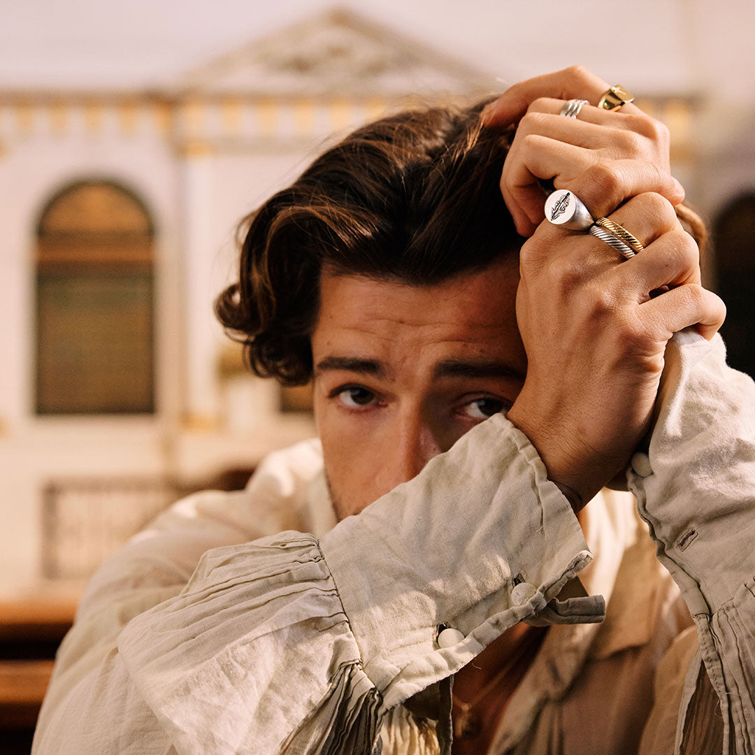Man adjusting his hair with a hand wearing Silver rings