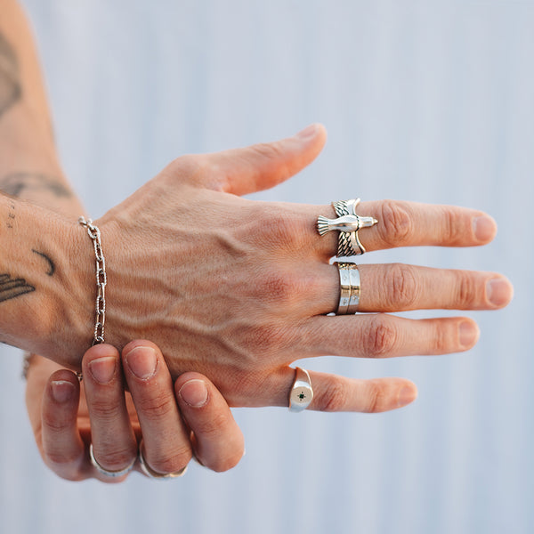 A male's hand wearing a selection of Sterling Silver rings, including the Dove Ring