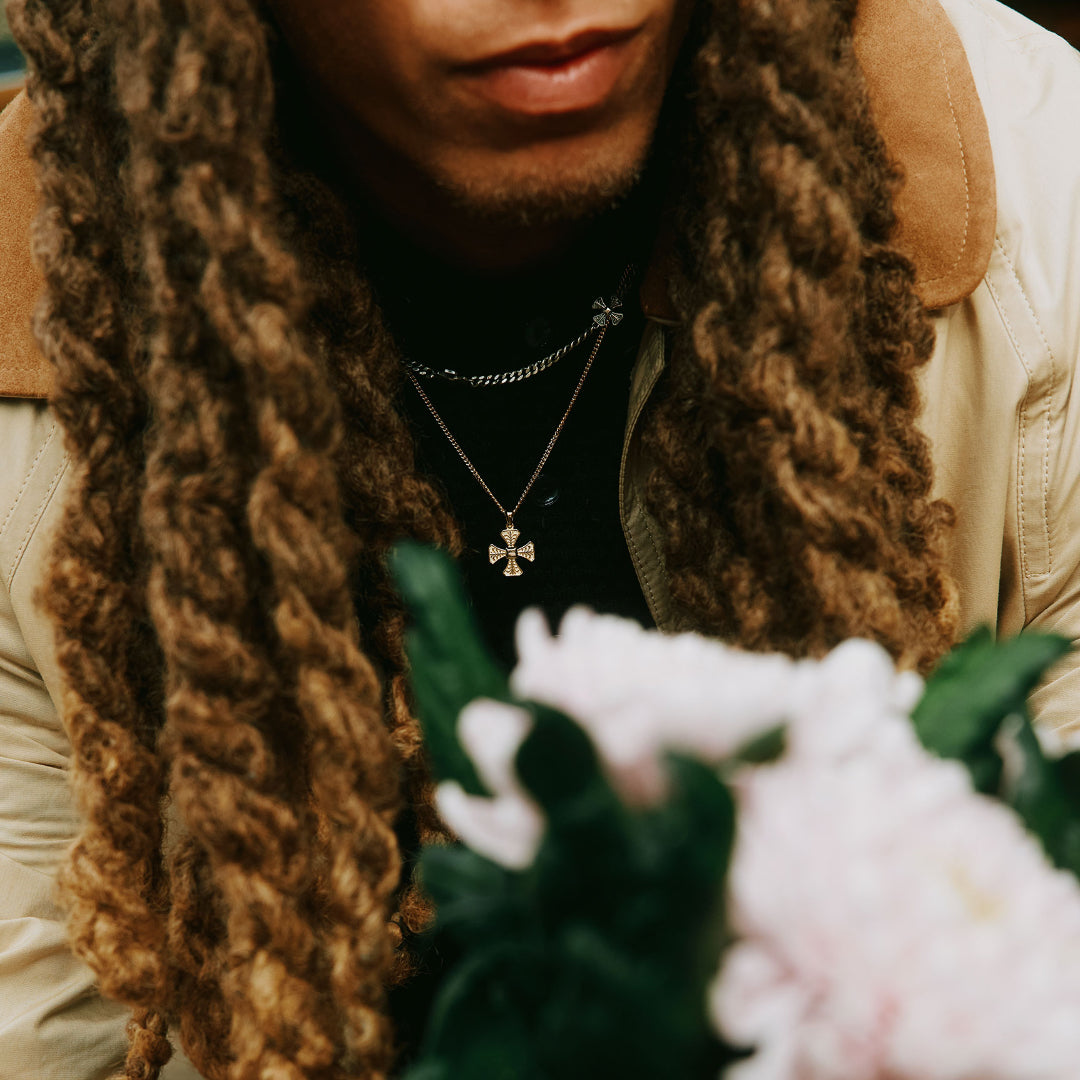 Person with long hair leans forward showing 2 necklaces