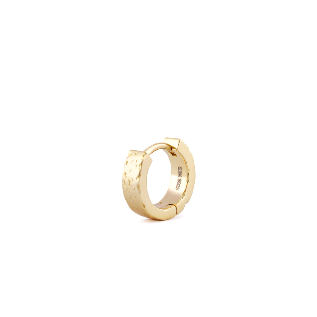 Gold huggie earring with rough texture standing on white background - Serge DeNimes