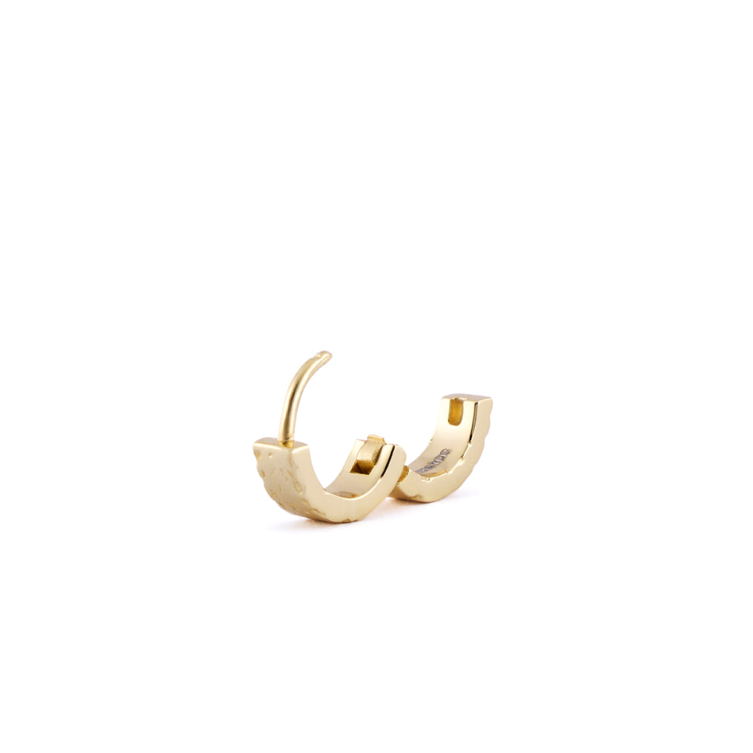 Gold huggie earring with rough texture standing on white background - Serge DeNimes
