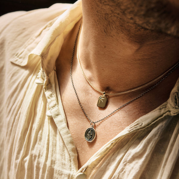 Close-up of a person wearing multiple necklaces with pendants.