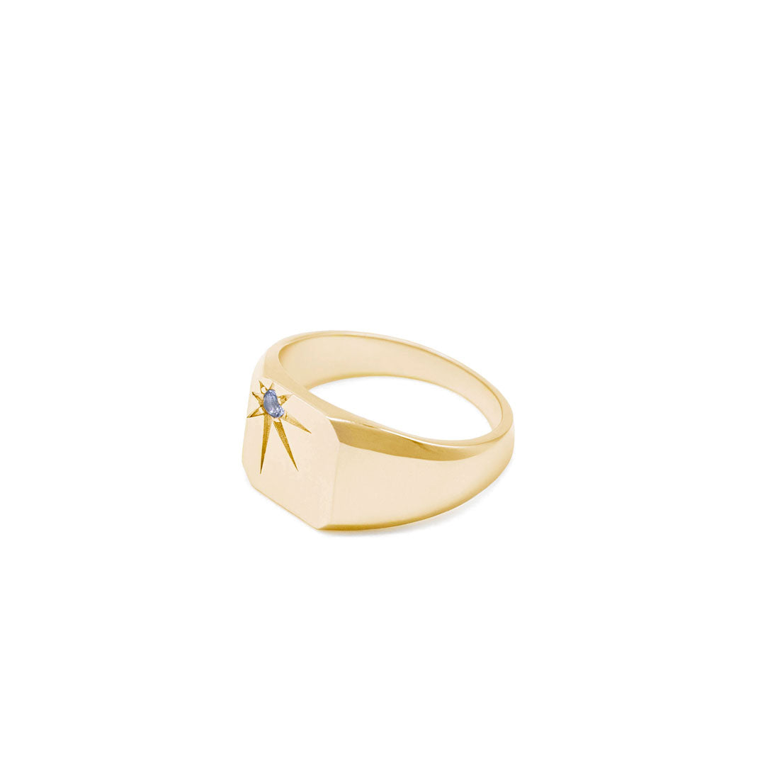Gold plated silver ring with a blue gemstone in an oversized star setting on a white background