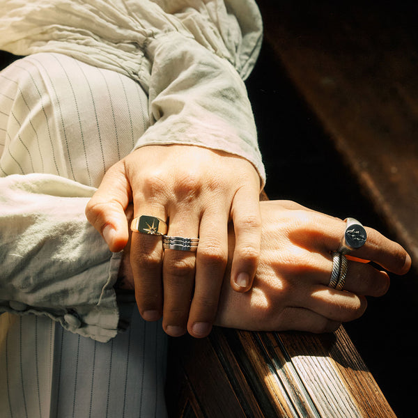 Close-up of two hands with rings on a wooden surface