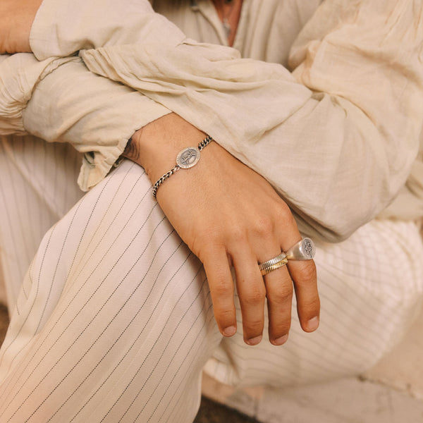Close-up of a person's hand wearing two Silver rings and Silver bracelet with a neutral background