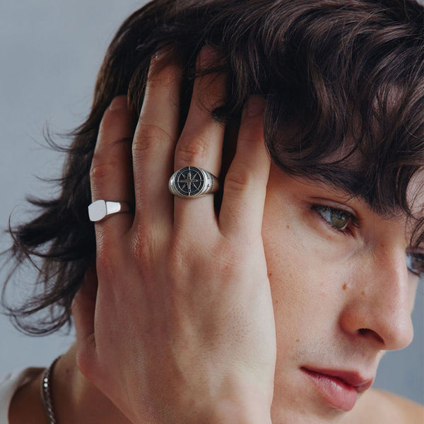 Model with shaggy hair wearing 2 rings on his fingers, Silver Signet Ring & Silver Napoleon Ring by Serge DeNimes