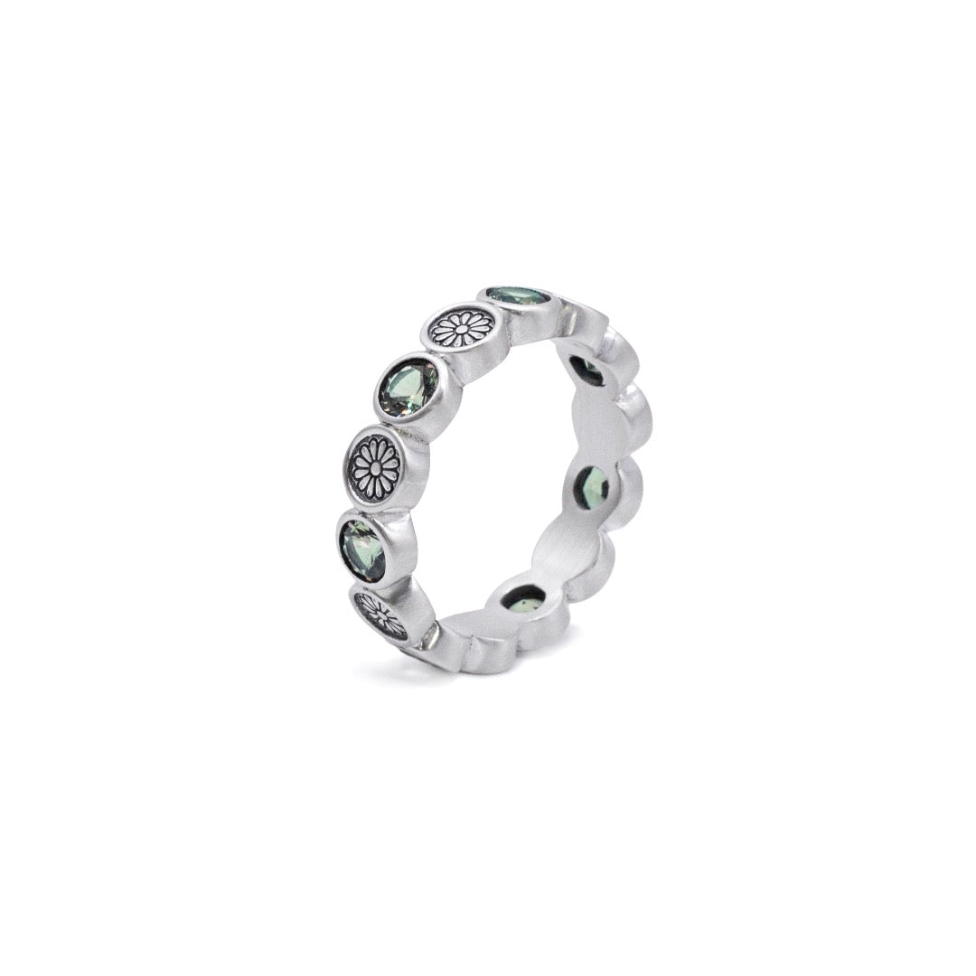 Silver ring with embedded stones standing on a white background