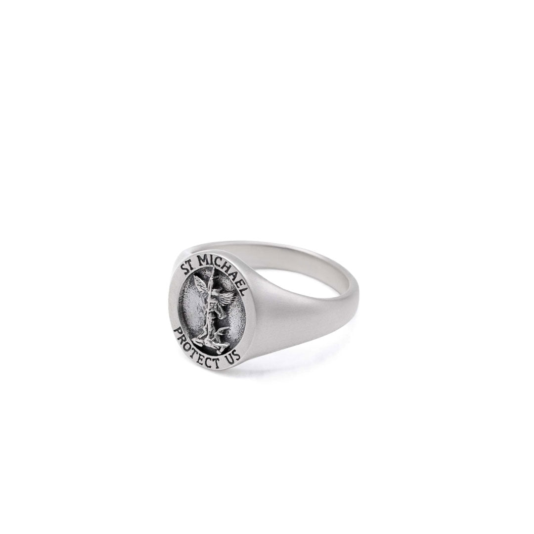 Silver ring with a depiction of St Michael on the face sitting on a white background by Serge DeNimes