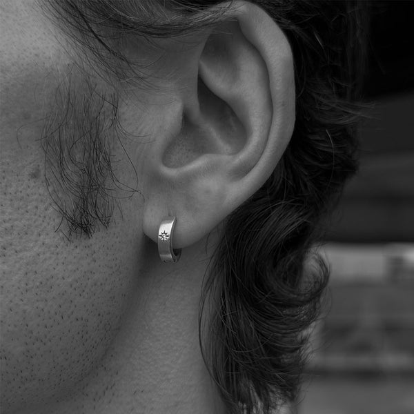 Black & White close up photo of a model wearing a huggie earring in his ear lobe