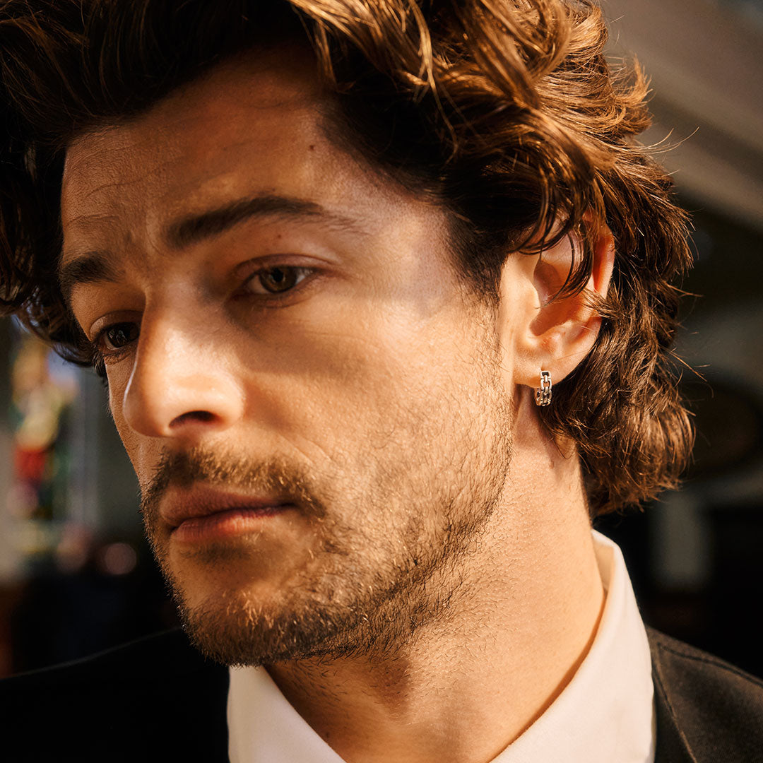 Close-up of a man with styled hair and a silver earring in his lobe