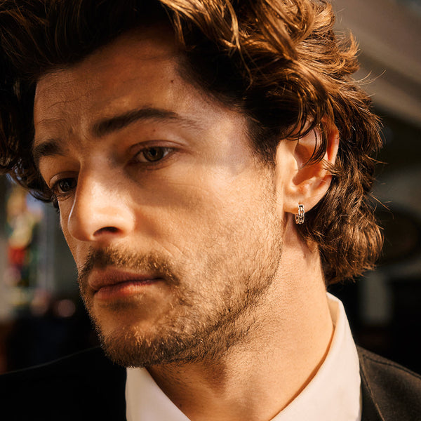Close-up of a man with styled hair and a silver earring in his lobe