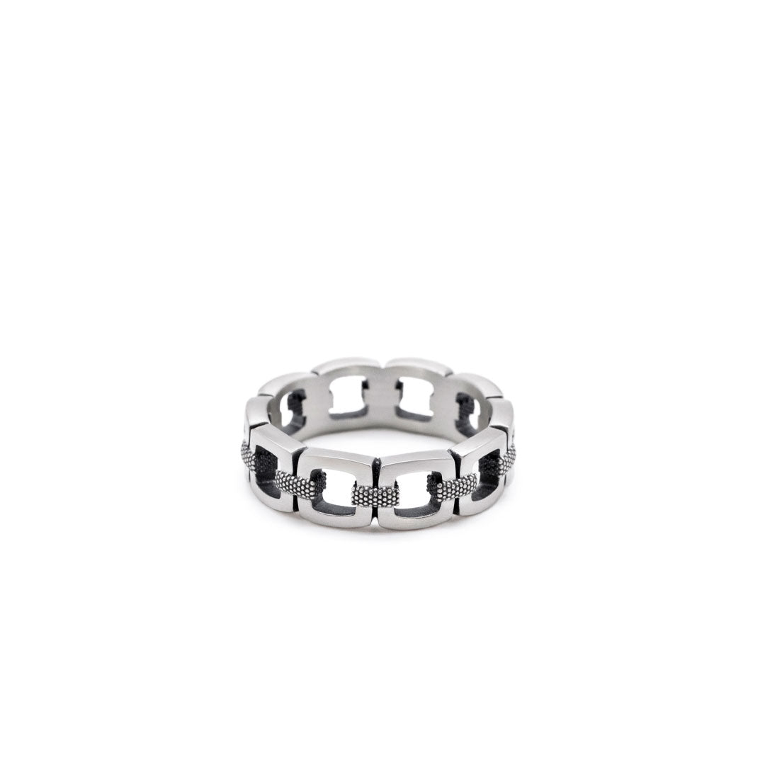 Silver chain-link ring on a white background by Serge DeNimes