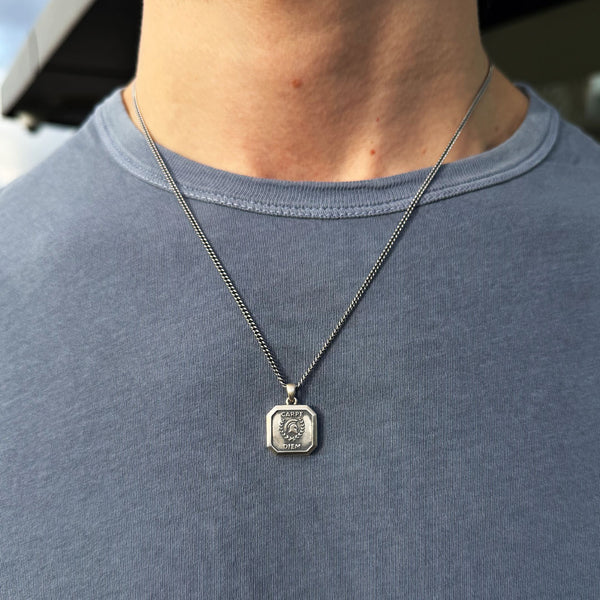 Close up of male wearing a blue tshirt wearing a Silver pendant necklace