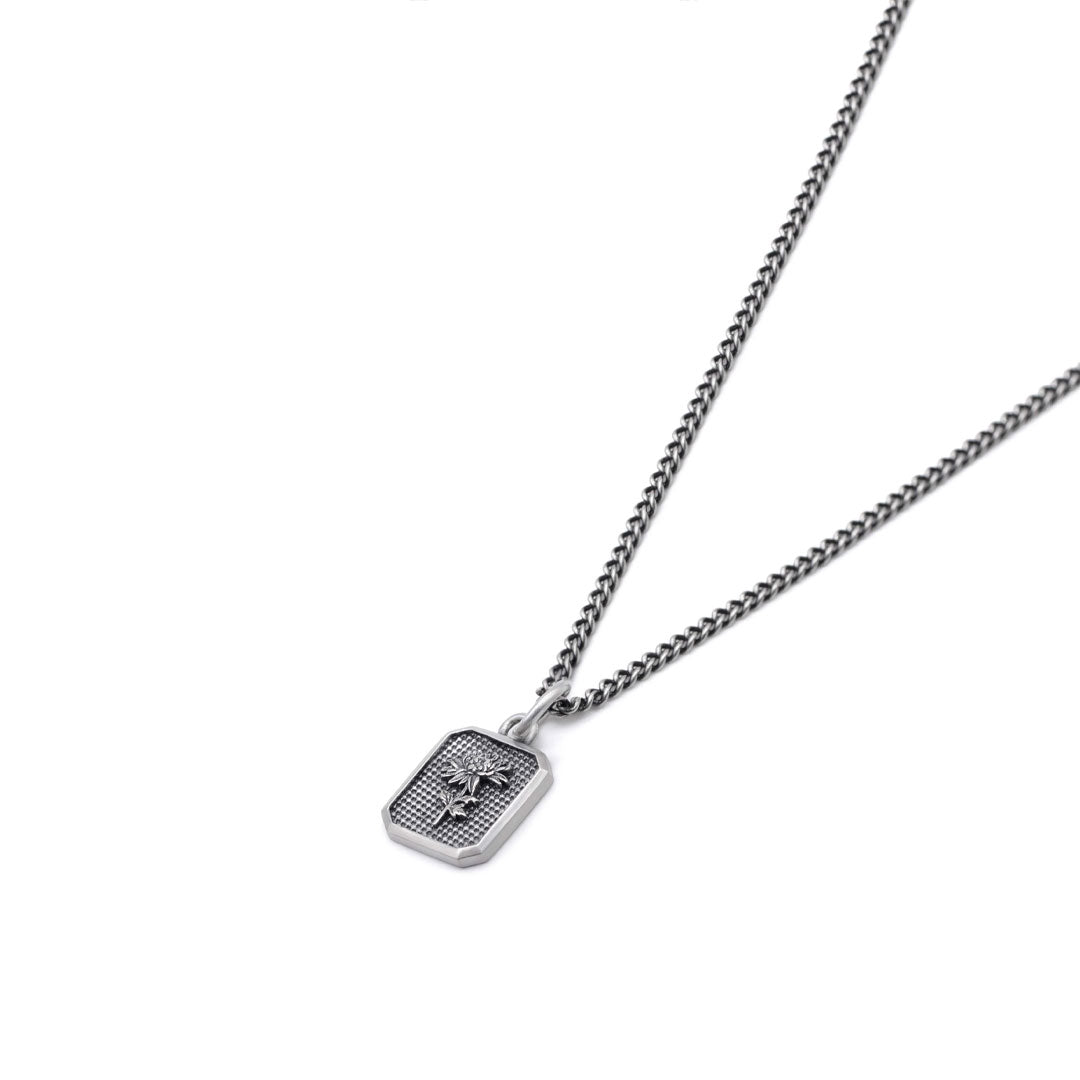 Silver necklace with a flower inside a rectangular pendant on a white background