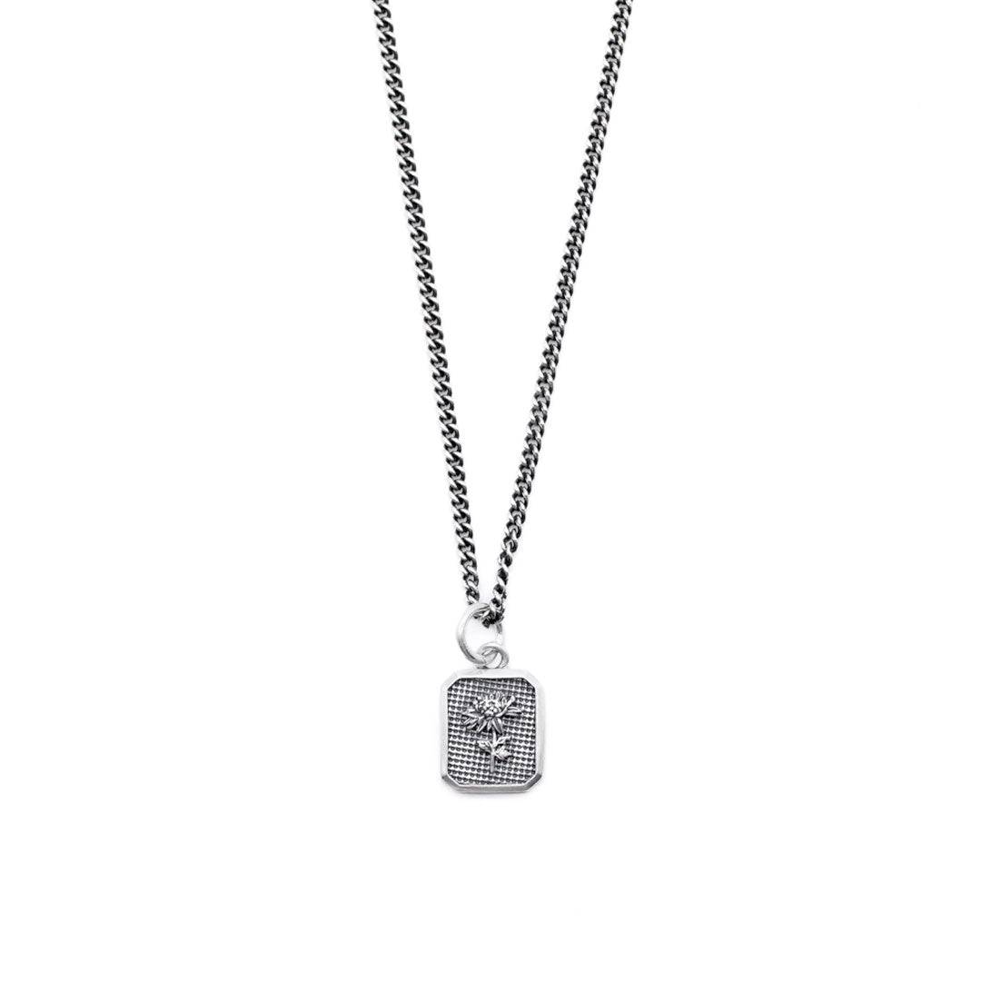 Silver necklace with a flower inside a rectangular pendant on a white background