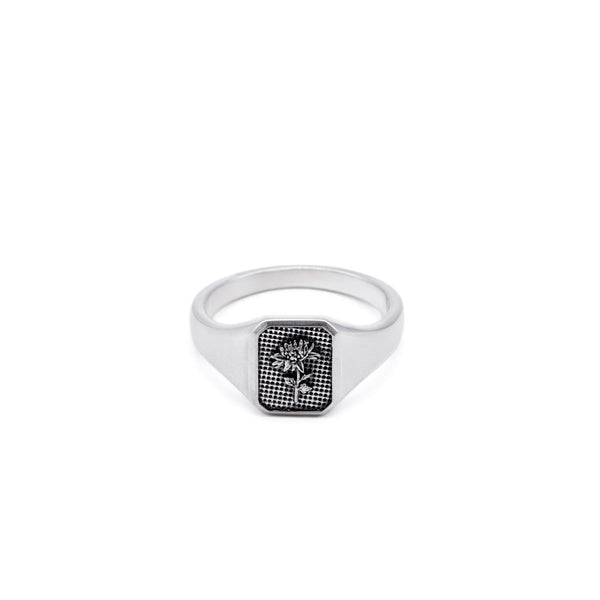 Silver ring with a flower inside a rectangle shaped face on a white background by Serge DeNimes