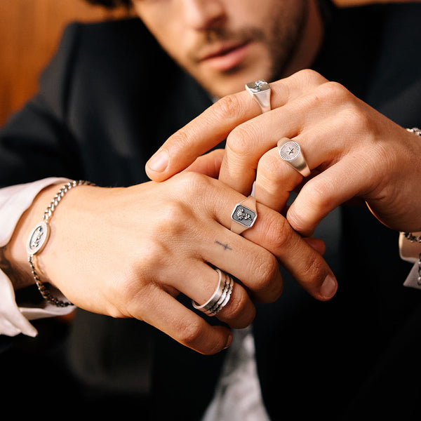 Close-up of hands with multiple Silver rings and bracelets, focusing on jewellery details.