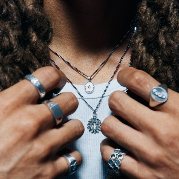 Close up of model with long dreadlocks wearing multiple rings and 2 pendant necklaces