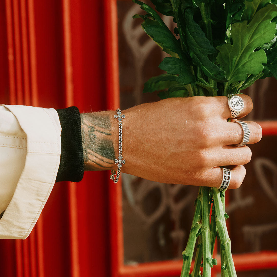 Models hand holding a bunch of flowers wearing multiple Silver rings and Silver bracelet