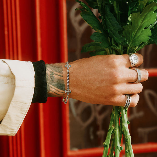 Models hand holding a bunch of flowers wearing multiple Silver rings and Silver bracelet