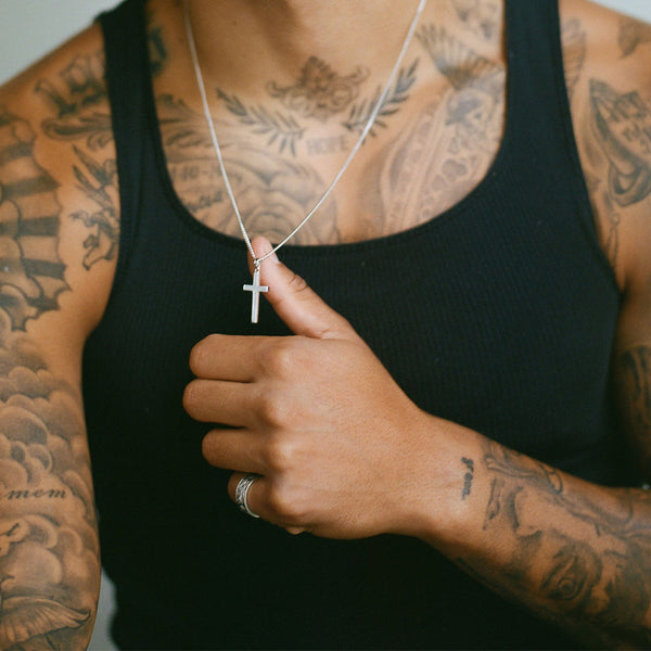Model wearing black vest and Serge DeNimes Silver Cross Necklace