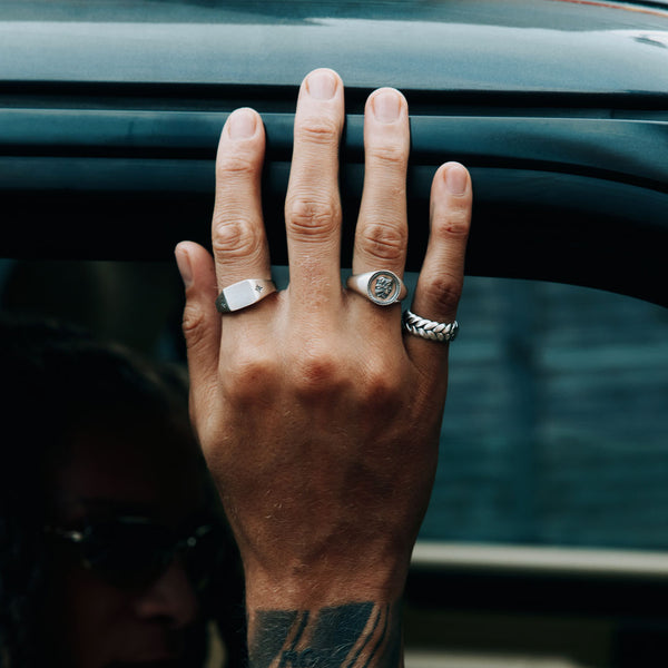 Male model hand resting on car wearing 3 Silver rings