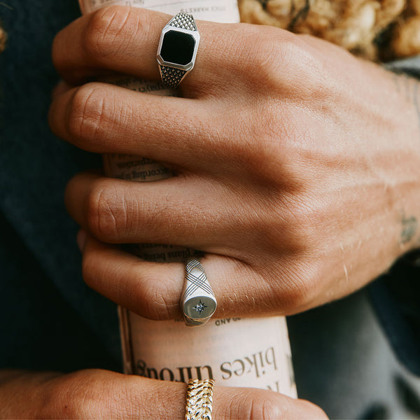 Model holding a newspaper wearing multiple Silver rings