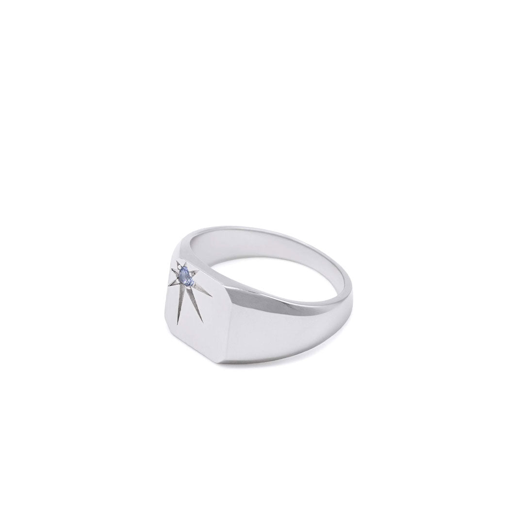 Silver ring with a blue gemstone in an oversized star setting on a white background