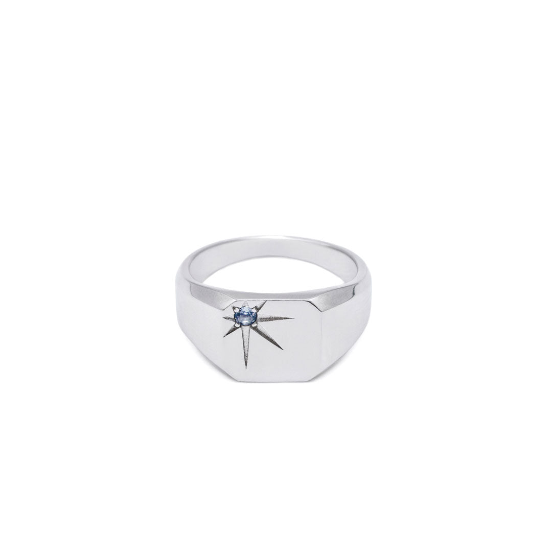 Silver ring with a blue gemstone in an oversized star setting on a white background