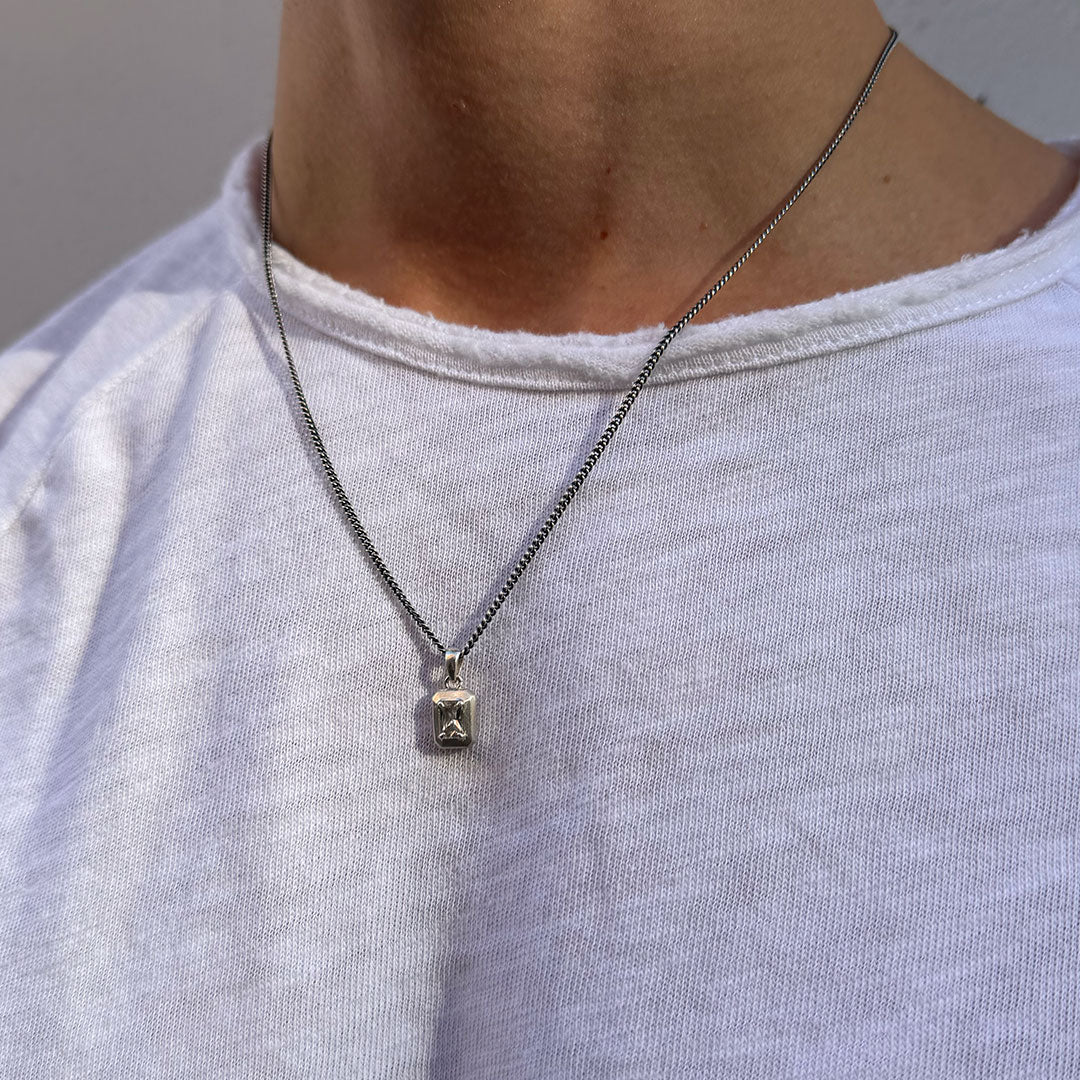 Model wears a white t-shirt under a Silver necklace with large clear gemstone - Serge DeNimes