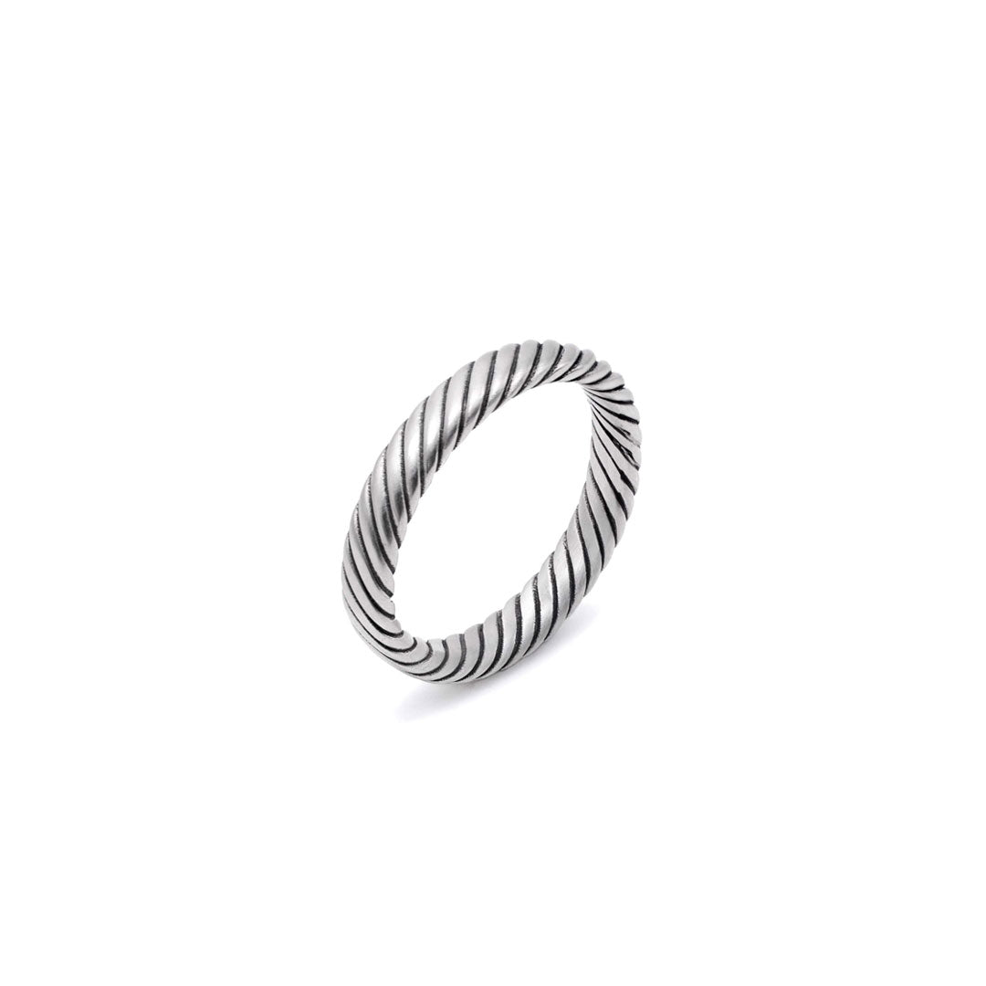 Silver band ring with a twist detail on a white background by Serge DeNimes