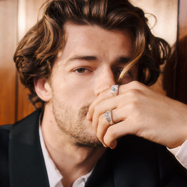 Man with styled hair wearing two rings on his finger, close-up portrait.