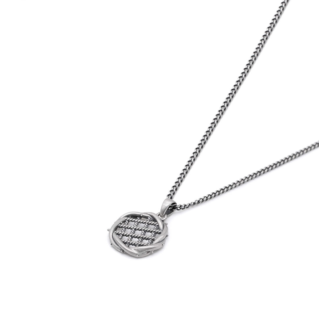 Silver necklace with grid detailing inside a round pendant pendant on a white background