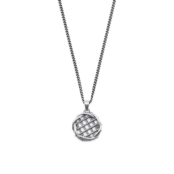 Silver necklace with grid detailing inside a round pendant pendant on a white background