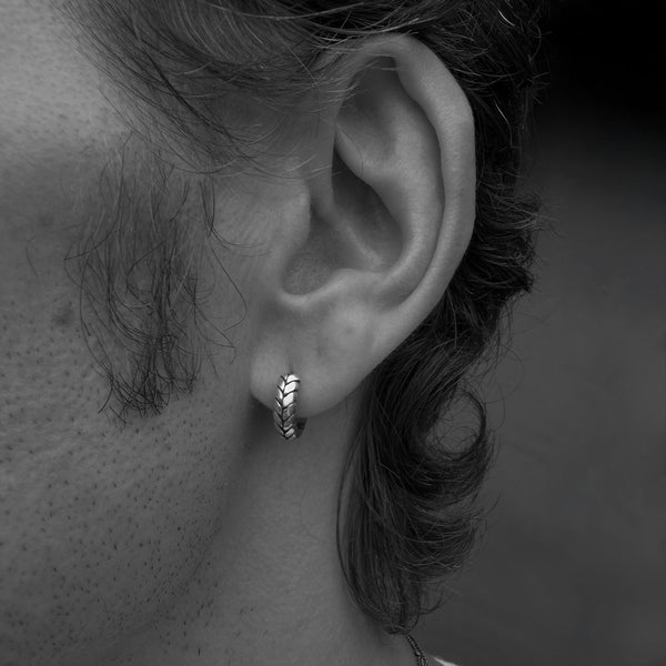 Close up of a male model wearing a silver hoop earring in his ear lobe
