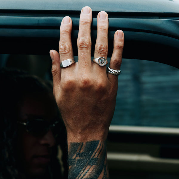 Male model hand resting on car wearing 3 Silver rings