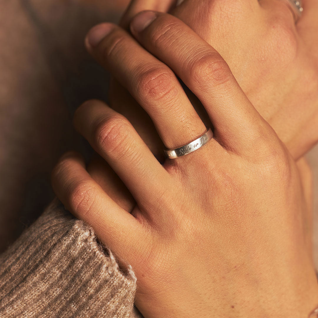 Model holds hands together wearing a Silver band ring with 'Ride or Die' engraved on it - Serge DeNimes
