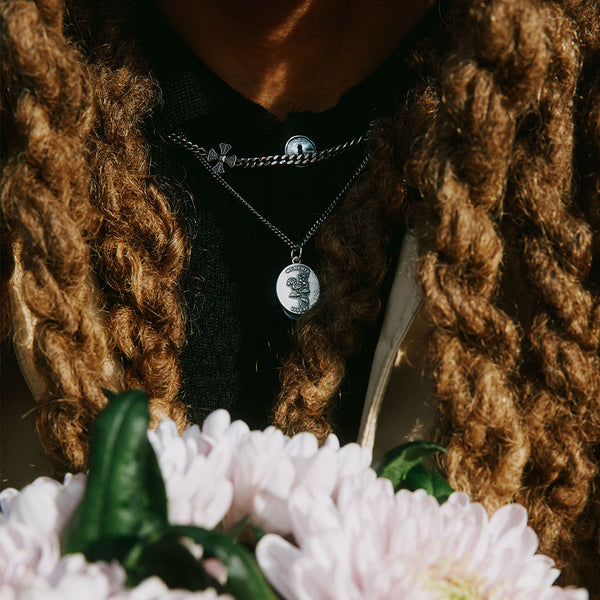 Model with long hair wearing black t-shirt under 2 Silver necklaces