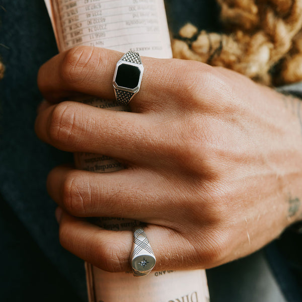 Model holds a newspaper wearing 2 Silver rings