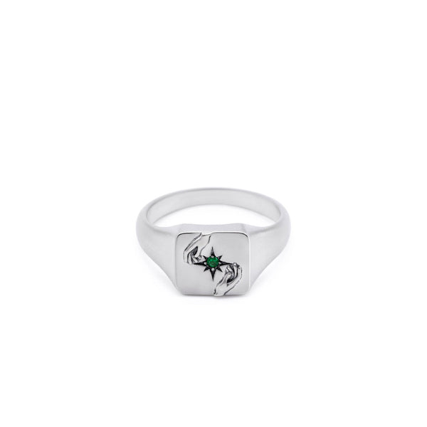Silver ring with 2 hands reaching for a green gemstone on a white background