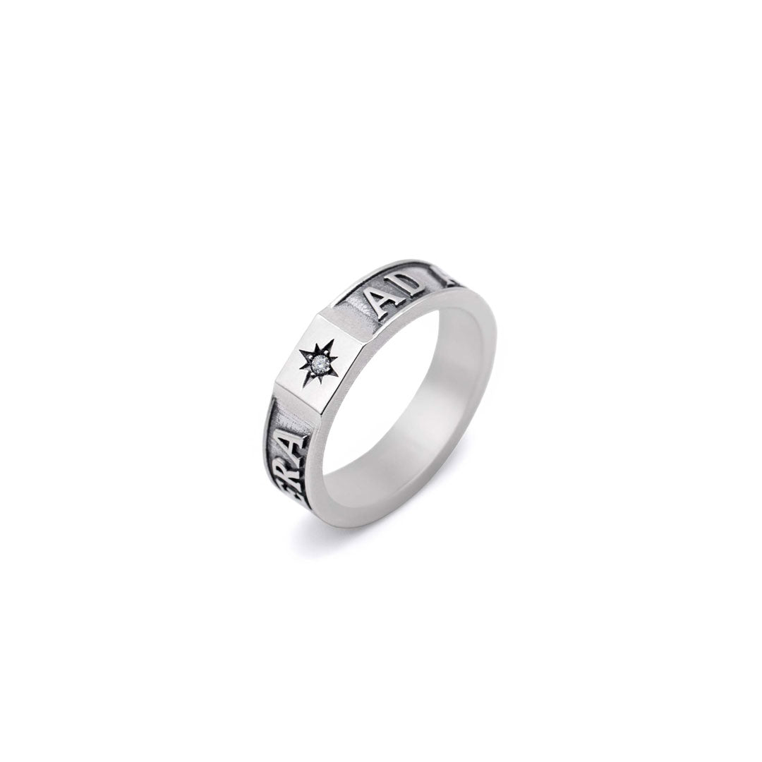 Silver ring with engraved text and a clear gemstone on a white background