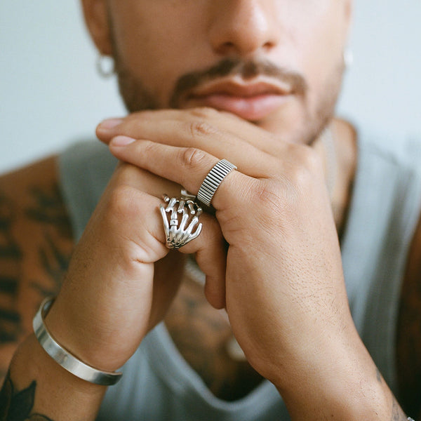 Model holding his hands wearing the Skeleton Hands Ring and Ridge Band Ring - Serge DeNimes