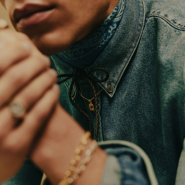 Close up of a person wearing a denim shirt with a pendant necklace on top
