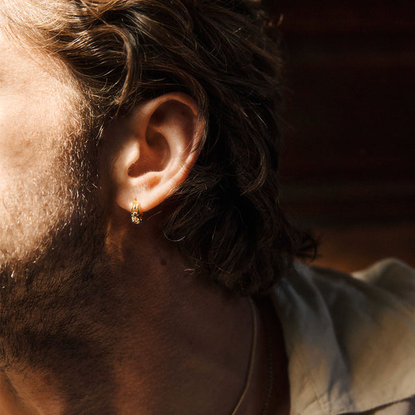 Close-up of a male's ear with a gold plated silver earring in his ear lobe