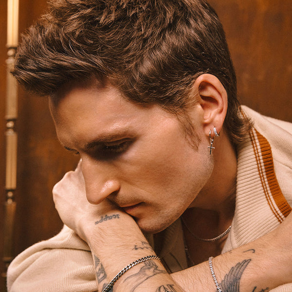 Male model wearing Sterling Silver hoop earring with small cross pendant in ear lobe